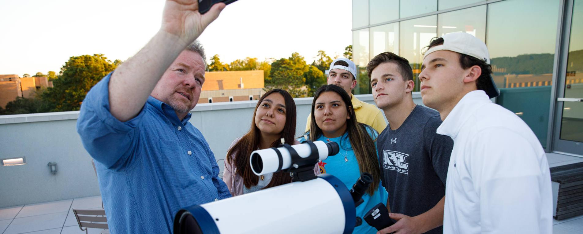 Dr. Dan Bruton demonstrates to a group of students how to use astronomy equipment