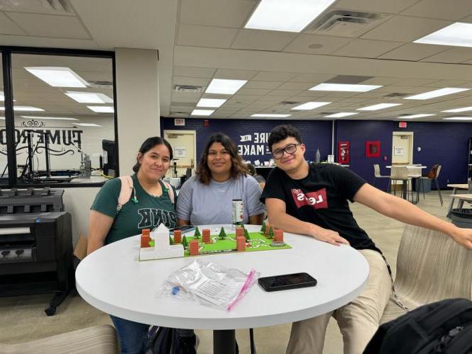 three students in Dr. Dan Li's art appreciation class at SFA and the functional art in the form of board game they created